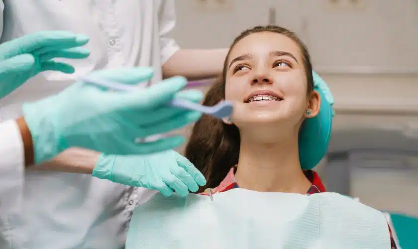 A dentist explaining TMJ care and night guard options to a teenager with jaw pain.